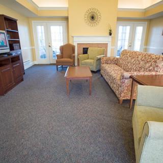 A cozy living room with sofas, a coffee table, and a television, centered around a fireplace.