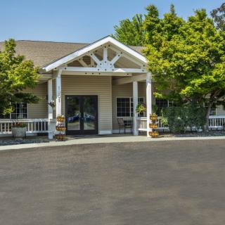 A well-maintained building entrance with a porch and surrounding trees.