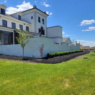 A beautifully designed house with modern architecture, surrounded by well-maintained landscaping and under a clear blue sky.
