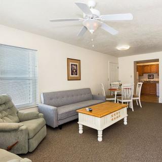 A cozy living room with a sofa, armchair, and coffee table, adjacent to a dining area.