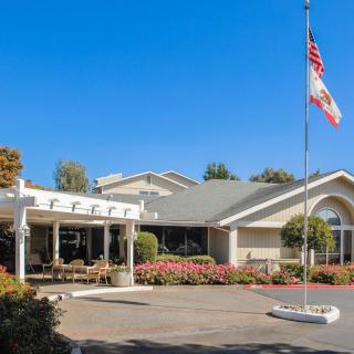 A building with a flagpole and garden in the foreground under a clear blue sky.