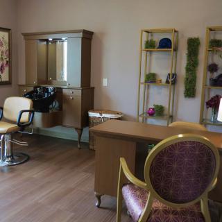 A cozy beauty salon interior with chairs, a mirror, and neatly organized shelves.