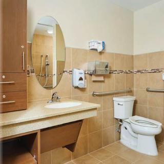An accessible bathroom equipped with handrails, a sink, and a toilet.