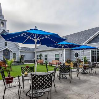 An outdoor patio with blue umbrellas, tables, and chairs next to a building.