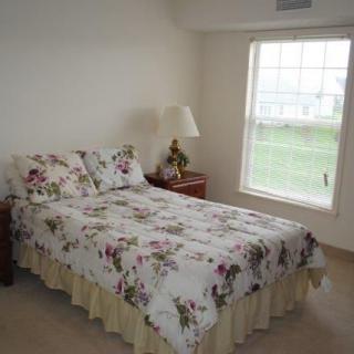 A cozy bedroom with a floral bedspread and a lamp by the window.