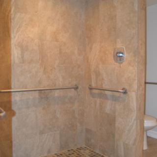 Accessible shower with grab bars and tiled walls.
