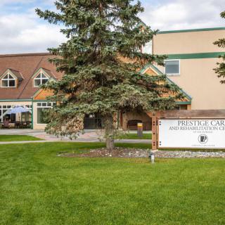A school building with a sign outside, surrounded by trees and grass.