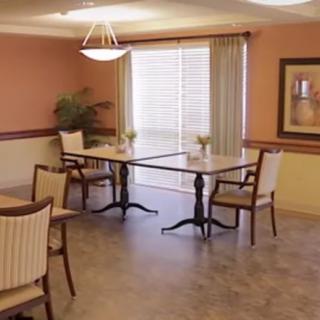 A neatly arranged dining area with tables and chairs, featuring a large window with curtains.
