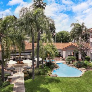 A serene tropical resort with a pool surrounded by palm trees and lush gardens.