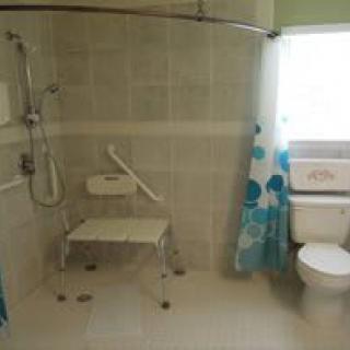 Accessible bathroom with a shower chair and grab bar.