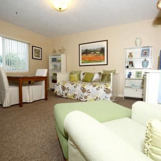 A cozy living room with a sofa, table, and shelves featuring decorative items.