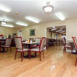 A spacious dining room with neatly arranged tables and chairs on a wooden floor.