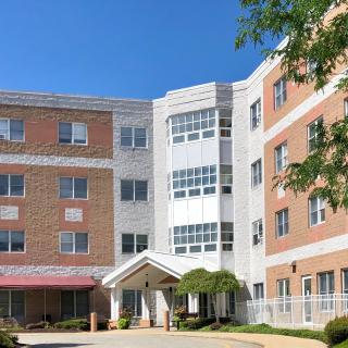 A multi-story residential building with a brick facade under a clear blue sky.