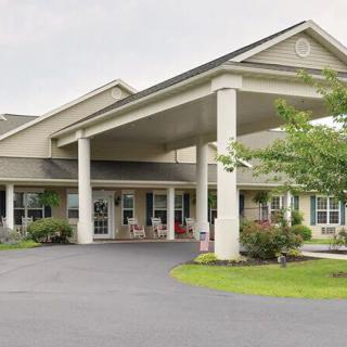 A building entrance with a covered driveway and surrounding greenery.