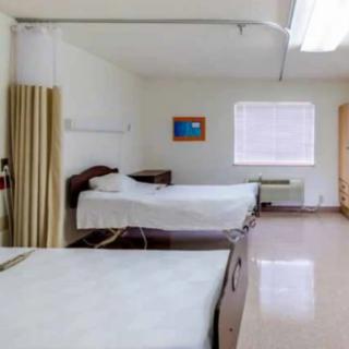 A clean and organized hospital room with two beds and a privacy curtain.
