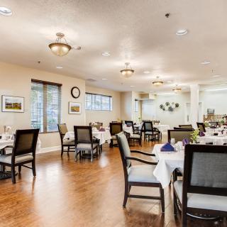 A well-lit dining room with neatly arranged tables and chairs, featuring a warm and inviting decor.