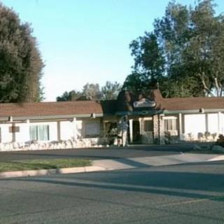 A street view of a one-story building with trees in the background.