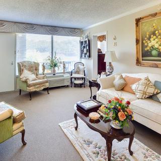 A cozy living room with classic decor featuring a sofa, armchairs, and a coffee table adorned with flowers.