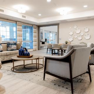 A modern living room with elegant furniture and neutral tones, featuring a seating area and decorative elements.