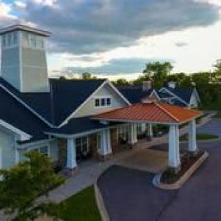 A beautifully designed building with a unique roof structure under a cloudy sky.