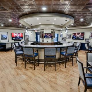 A modern bar with circular seating and multiple televisions on the walls.
