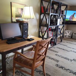 A cozy home office setup with a wooden desk, a computer, and a bookshelf.