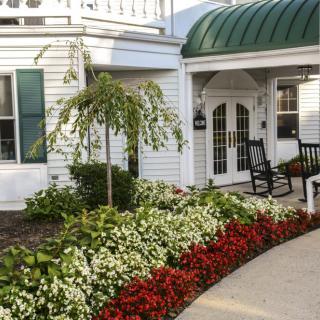 A charming house with a beautifully landscaped garden, featuring vibrant flower beds and a welcoming entrance.