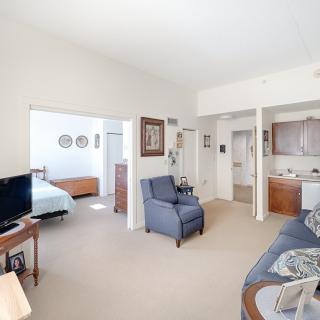 A cozy apartment living space with a view into the bedroom and a small kitchen area.