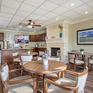 A cozy dining and kitchen area featuring wooden furniture, a fireplace, and a television.
