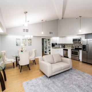 A modern open-concept living area featuring a cozy sofa, dining table, and a fully equipped kitchen.