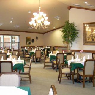 An elegant dining room with neatly arranged tables and chairs, illuminated by chandeliers.