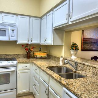 A modern kitchen with white cabinets and granite countertops.