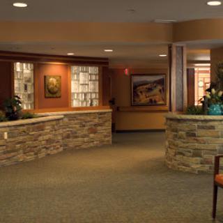 A welcoming lobby featuring a stone reception desk, decorative artwork, and plants.