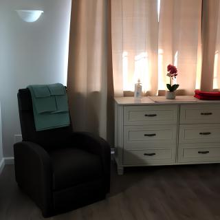 A cozy living room corner with an armchair and dresser by the window.