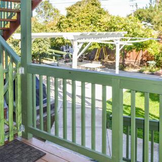 A view from a porch overlooking a green backyard with a wooden fence and garden.