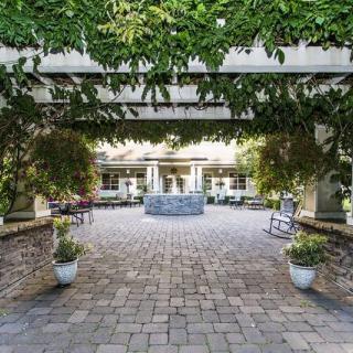 A serene courtyard featuring a central fountain surrounded by greenery and archways.