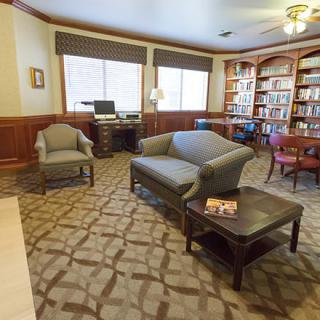 A cozy living room with bookshelves, a couch, an armchair, and a computer desk.