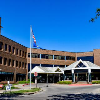 A modern hospital building featuring a welcoming entrance and clear blue skies.