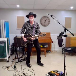 A musician performing with an acoustic guitar in a music studio setting.