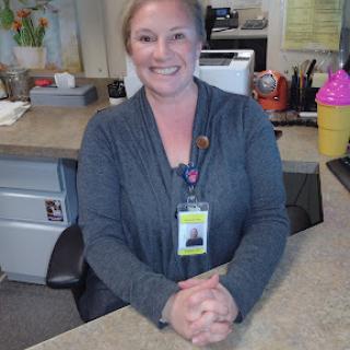 A cheerful receptionist welcoming visitors at her desk.