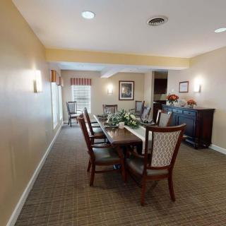 A well-furnished dining room with a long table and chairs, featuring elegant decor and carpeting.