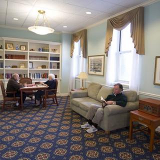 A quiet library reading room with people seated, enjoying their books.