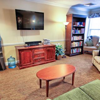 A cozy living room with a mounted TV, bookshelf, and comfortable seating.