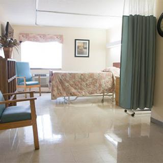 A quiet hospital patient room featuring a bed, armchair, and privacy curtain.