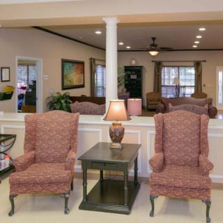 A cozy lobby area featuring two upholstered chairs with a lamp on a table between them.