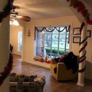 A cozy living room adorned with festive holiday decorations, featuring a large window display and comfortable seating.