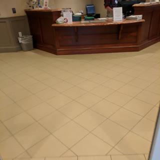 A view of a reception area featuring tiled flooring and a wooden front desk.