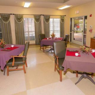 An inviting dining room with tables adorned with purple tablecloths and red placemats.