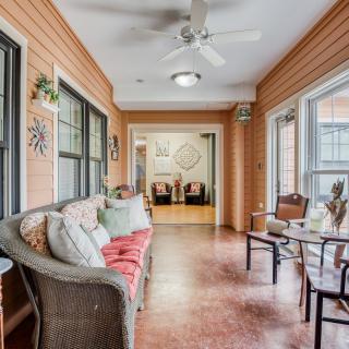 A cozy sunroom featuring wicker furniture, large windows, and a ceiling fan.