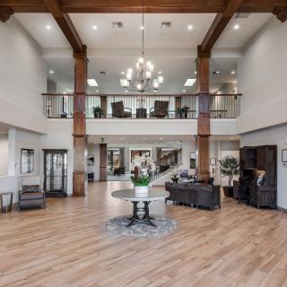 A spacious and modern lobby with a high ceiling, featuring wooden beams and a central chandelier.